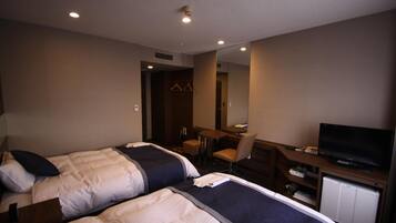 A hotel room with two beds, a desk with a television, and a mirror.