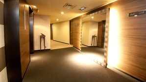 Un pasillo moderno de hotel con paneles de madera, un espejo y un cartel con los números de las habitaciones.