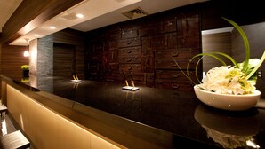Un moderno espacio de bar con una encimera oscura, varios cajones y un cuenco con flores blancas.