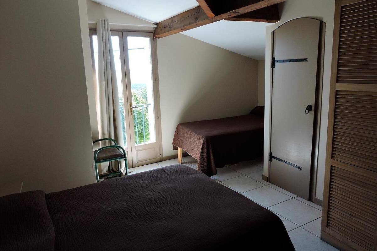 Une chambre à coucher comprenant un lit, une chaise, une armoire et une porte coulissante donnant sur un balcon.