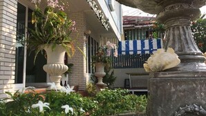 Un bâtiment à la façade en briques, agrémenté de grands pots de plantes et d’une fontaine.