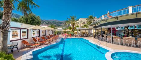 Una piscina al aire libre, sombrillas, tumbonas