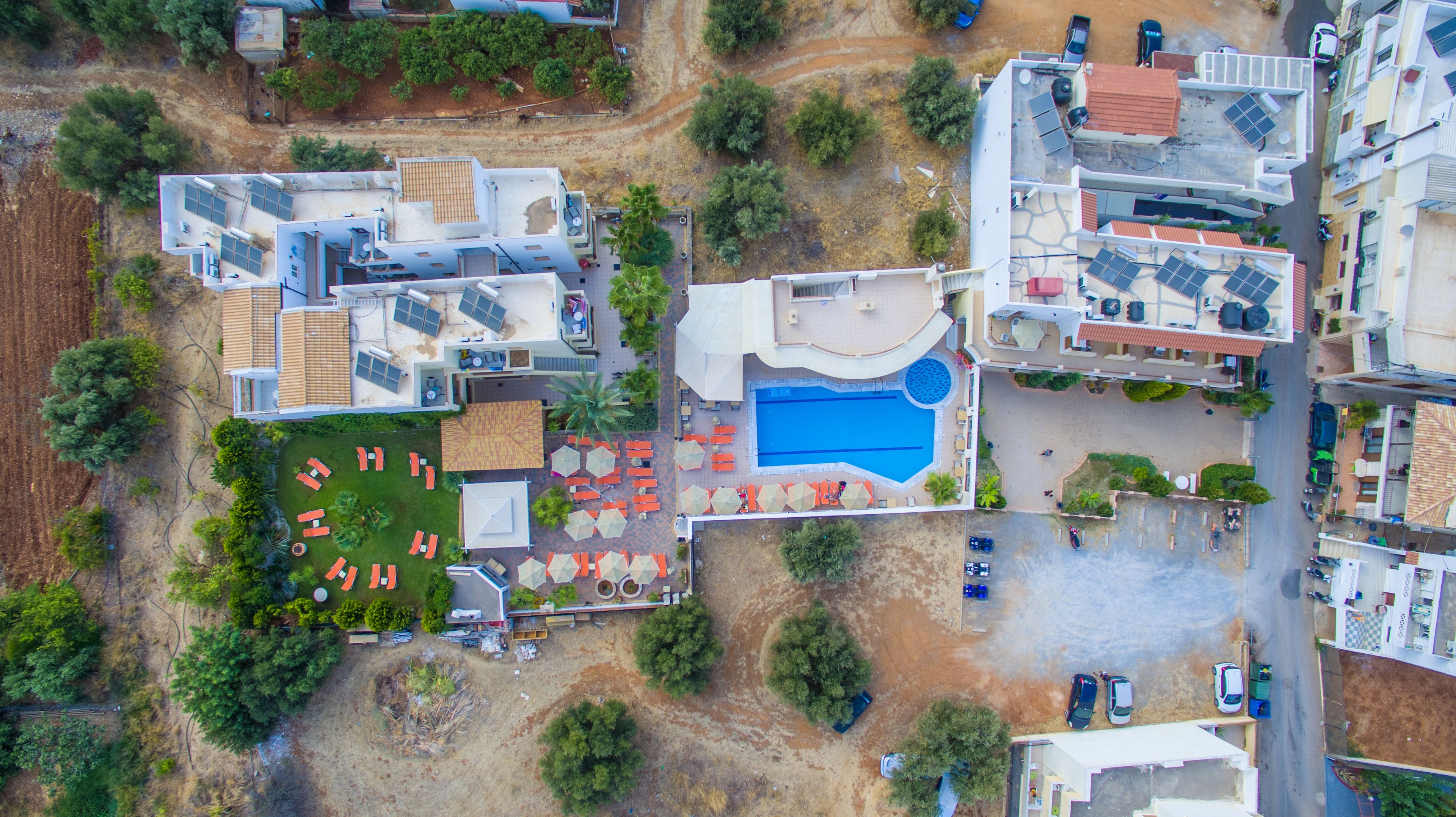 An aerial view of a hotel with multiple buildings, a swimming pool, and outdoor seating areas.