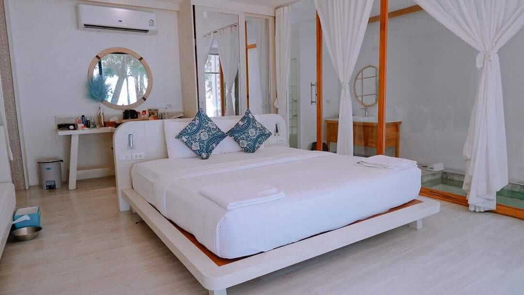 Un dormitorio moderno con una cama grande, una mesita de noche, un espejo y una ventana con cortinas.