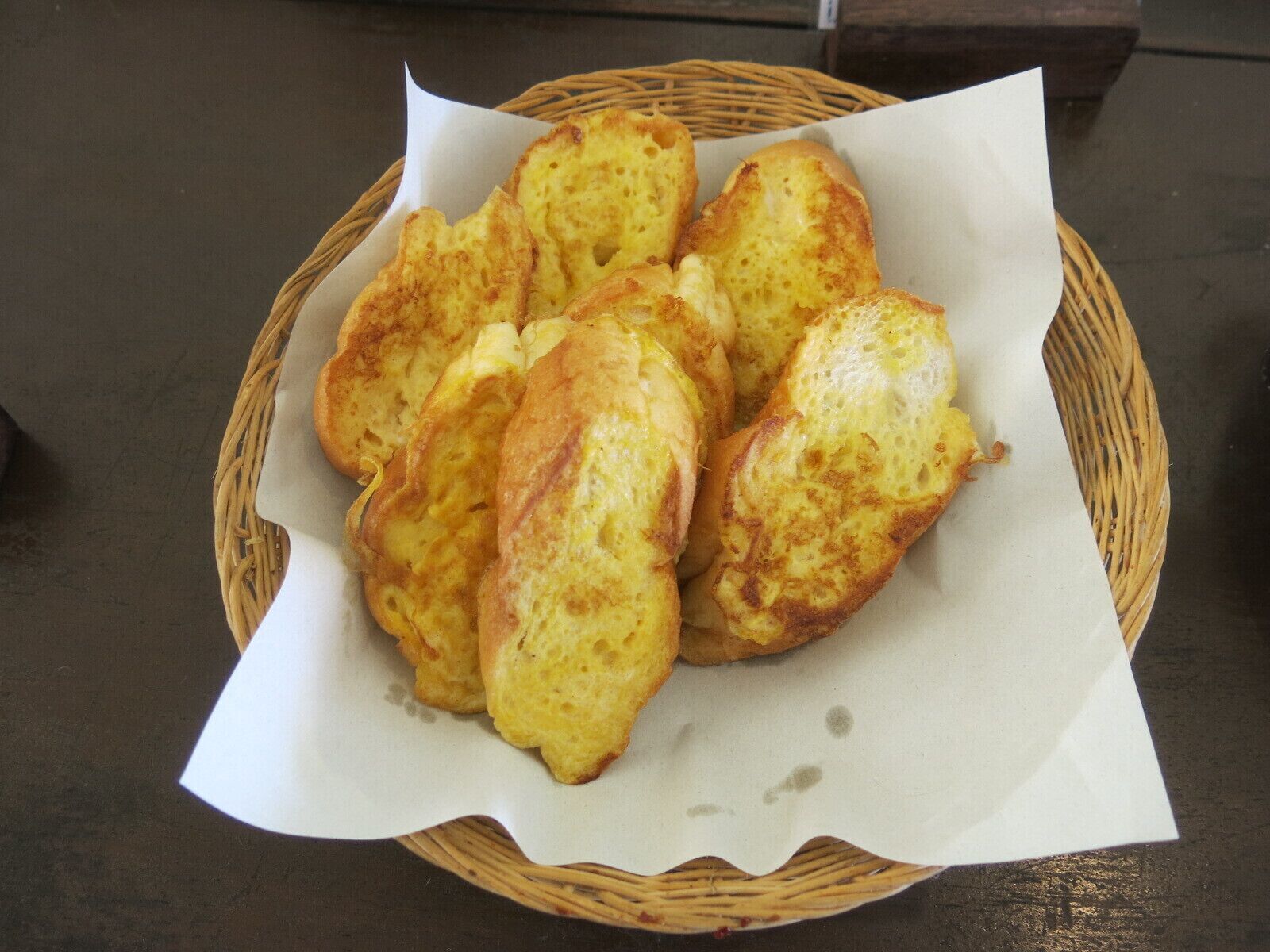 A basket of golden-brown bread rolls on a table.
