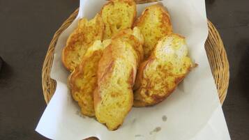 A basket of golden-brown bread rolls on a table.
