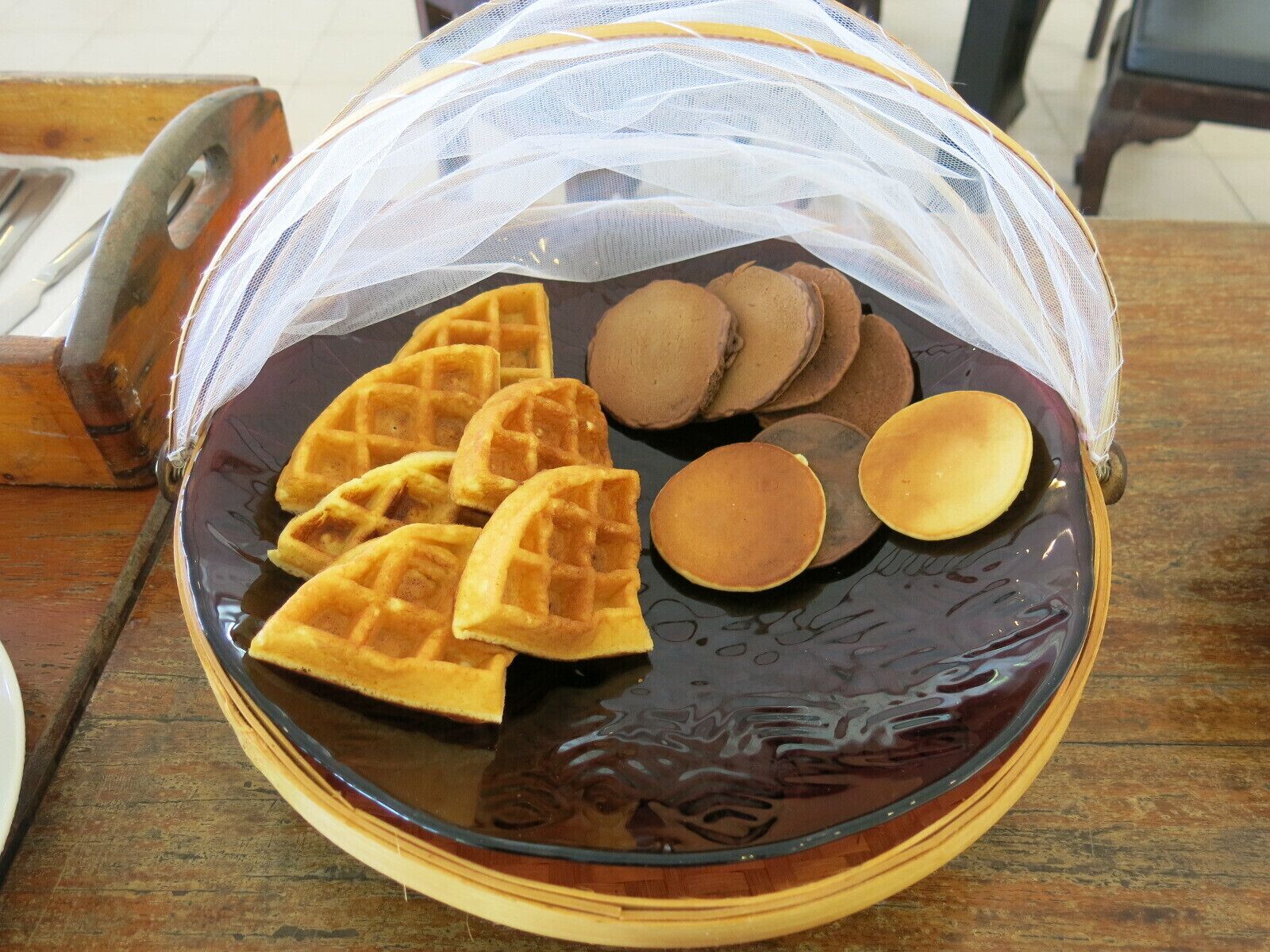 A plate of waffles and pancakes on a wooden table.