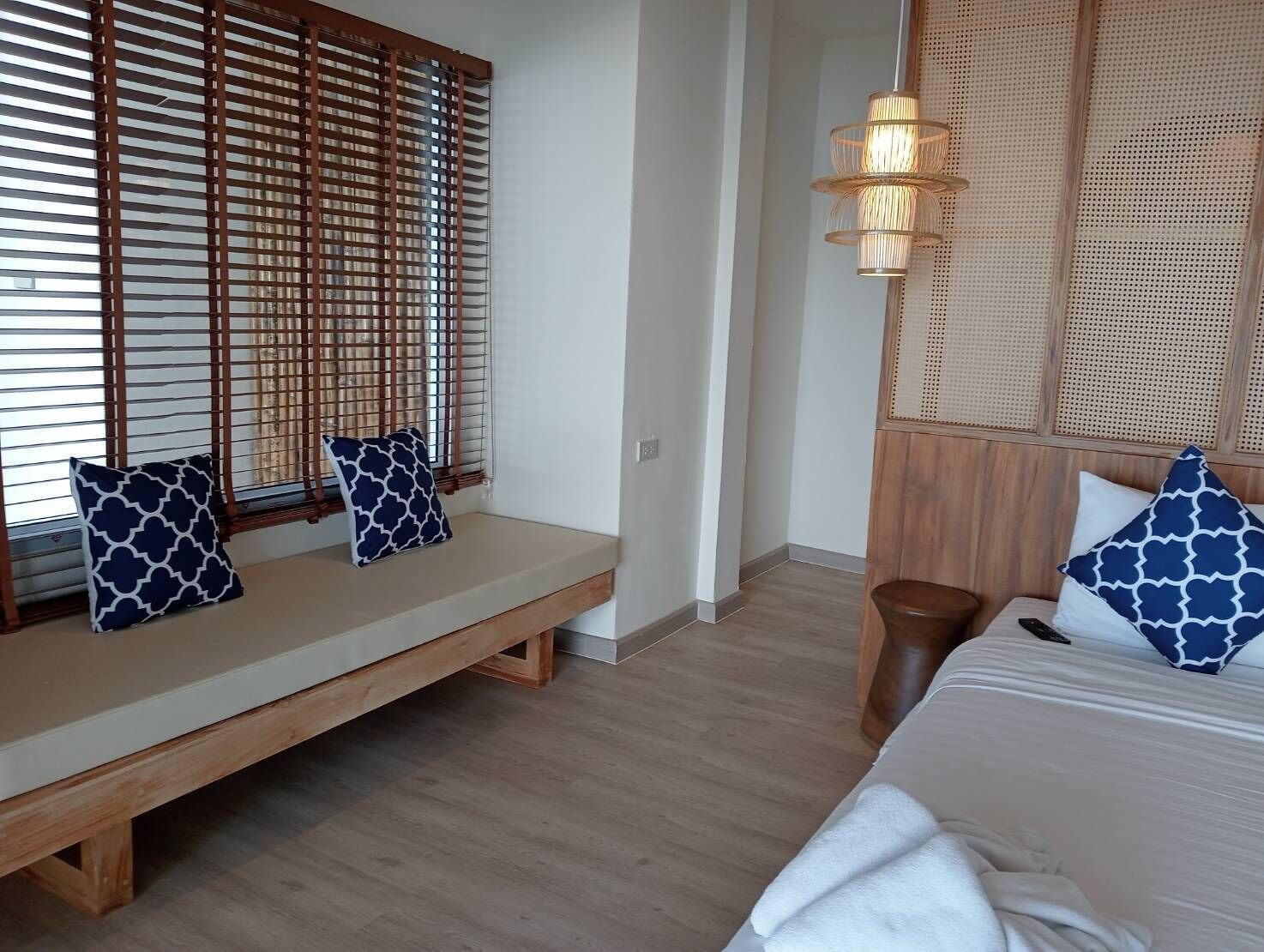 Una habitación con un banco de madera, una cama con cabecera y un panel de pared tejido.