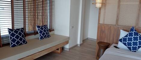 Una habitación con un banco de madera, una cama con cabecera y un panel de pared tejido.