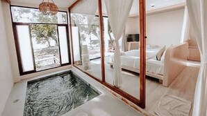 A bedroom with a large window, a small indoor pool, and a bed with white bedding.