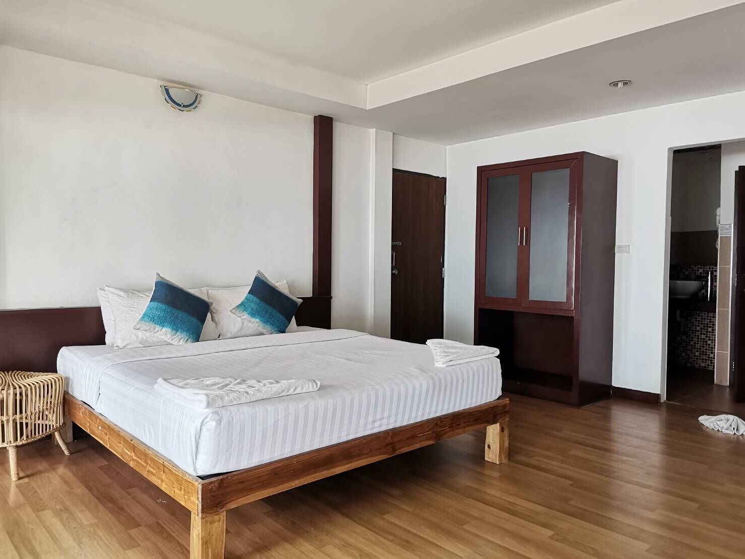 A bedroom with a wooden bed, white bedding, and a wooden wardrobe.