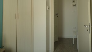 A room with a ceiling fan, an air conditioning unit, a door leading to another room, and a small table.