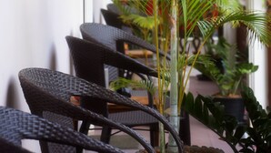 A hallway with wicker chairs and a tall potted plant.
