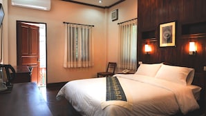 A hotel room with a bed, a chair, a desk, and a telephone.