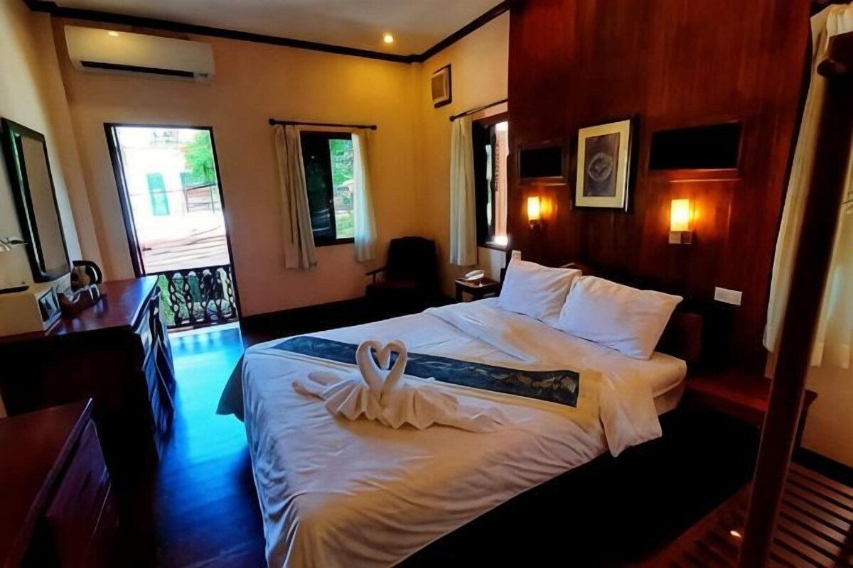 A hotel room with a bed, a desk, a chair, and a window.