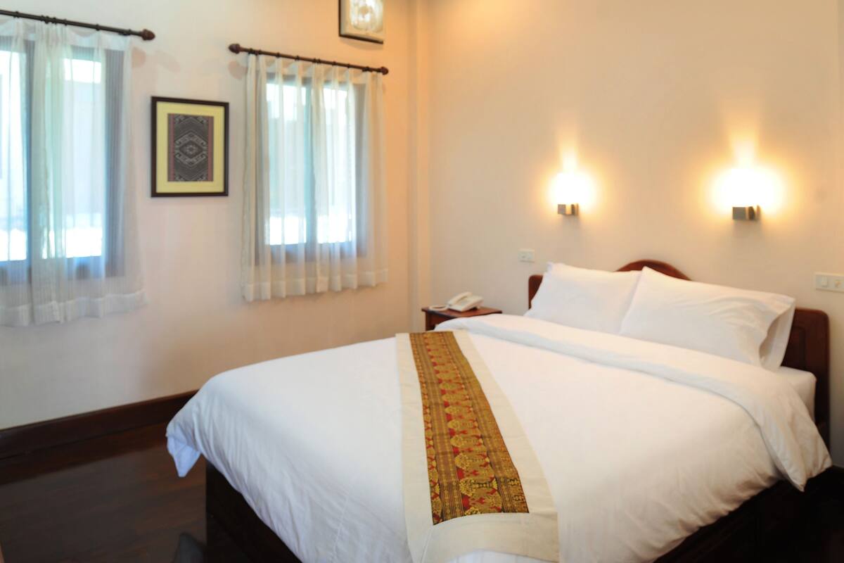A hotel room with a large bed, two bedside lamps, a nightstand, and a framed picture on the wall.