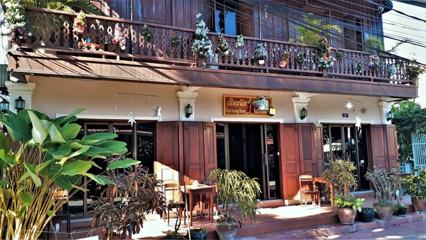 A traditional wooden building with a balcony decorated with Christmas ornaments and plants.
