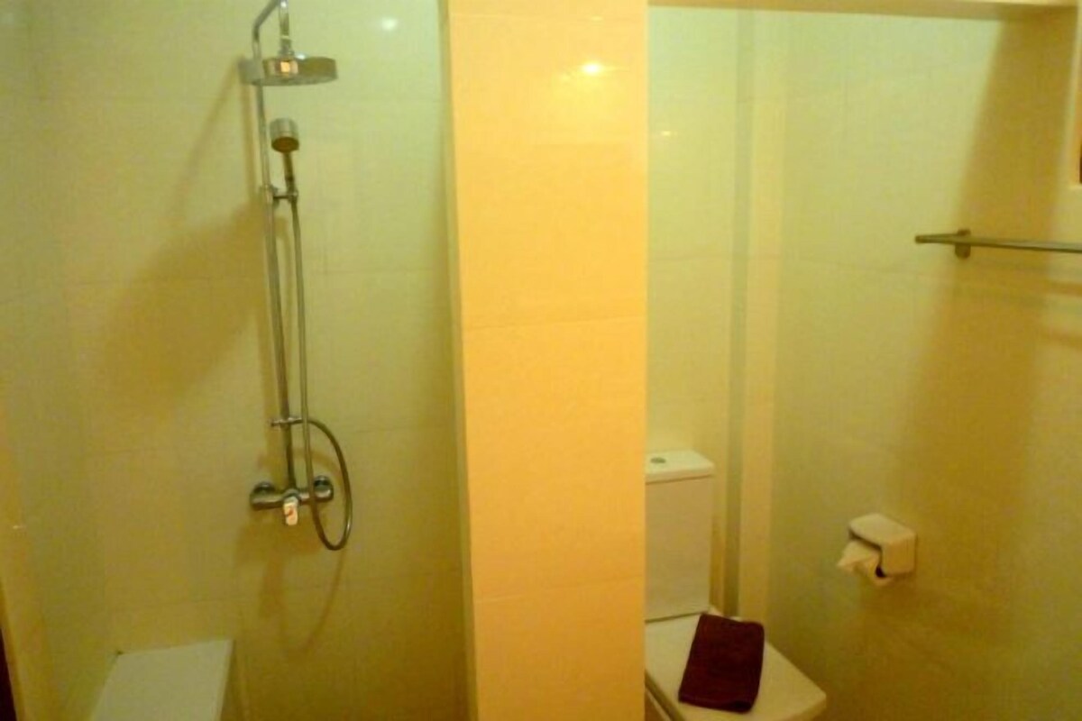A bathroom with a glass-enclosed shower, a toilet, and a towel rack.