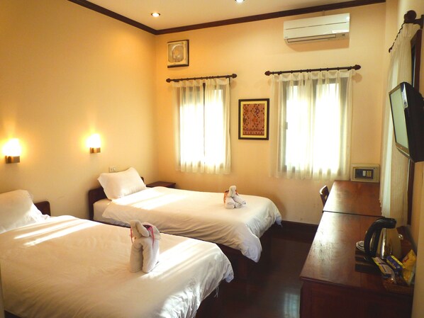 A hotel room with two beds, a desk with a kettle, a microwave, and a television.