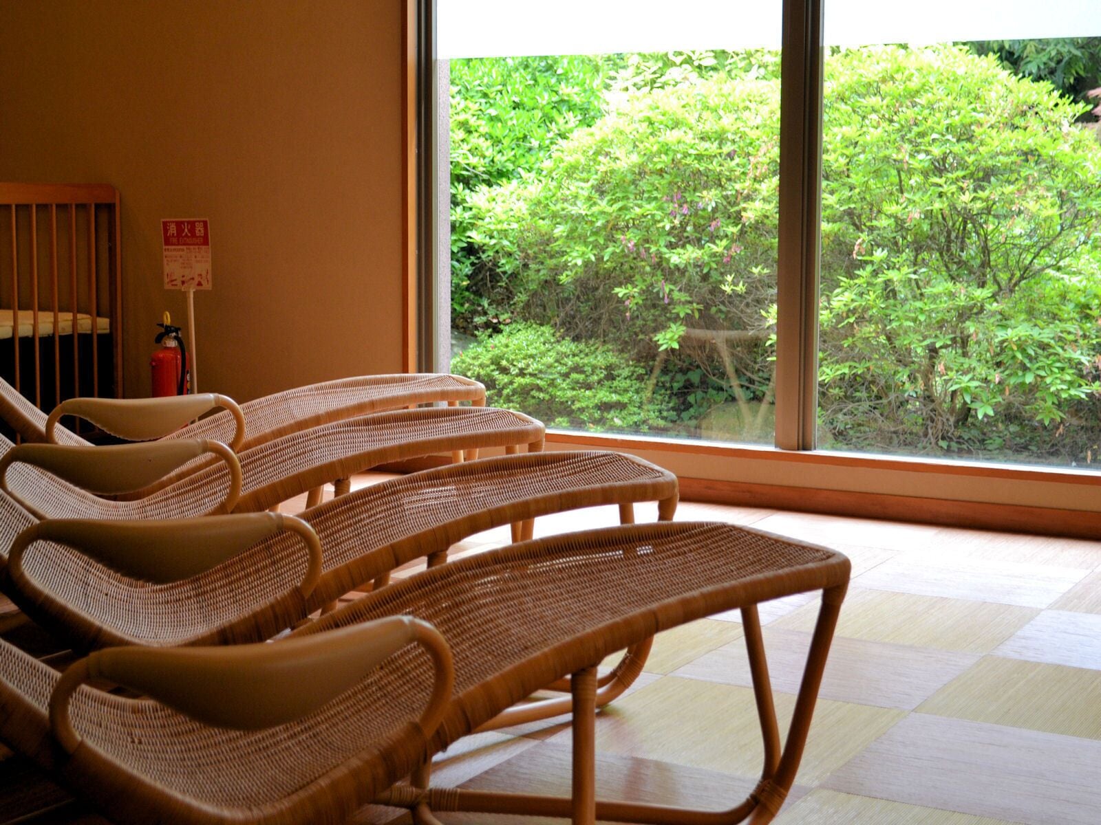 A room with wicker chairs and a large window offering a view of greenery outside.