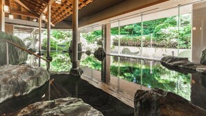 A tranquil indoor water feature with a wooden ceiling and large windows overlooking a lush garden.