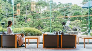 A serene indoor garden with seating areas and a view of a lush, green landscape.