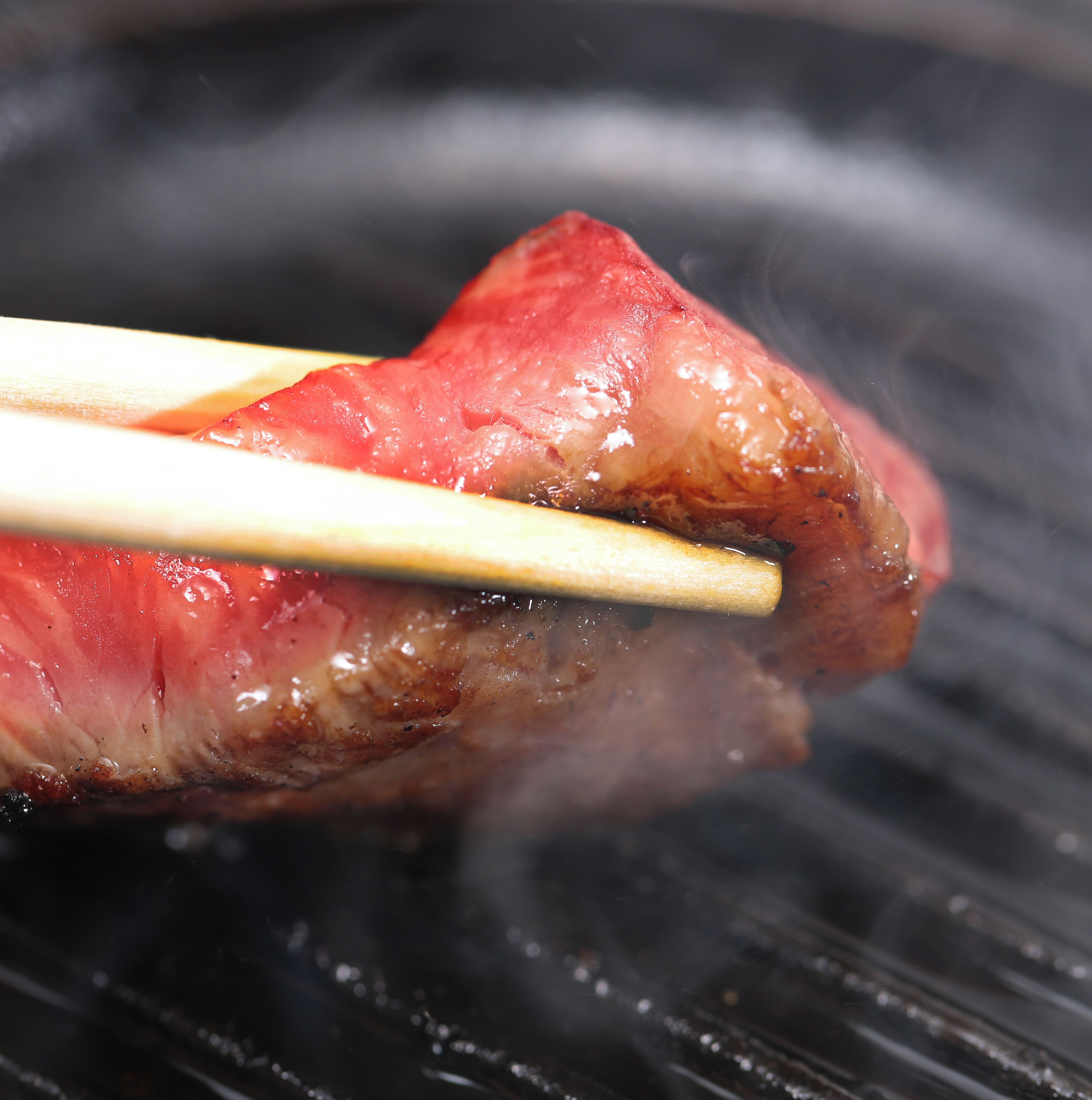 A close-up of a grilled meat with chopsticks.