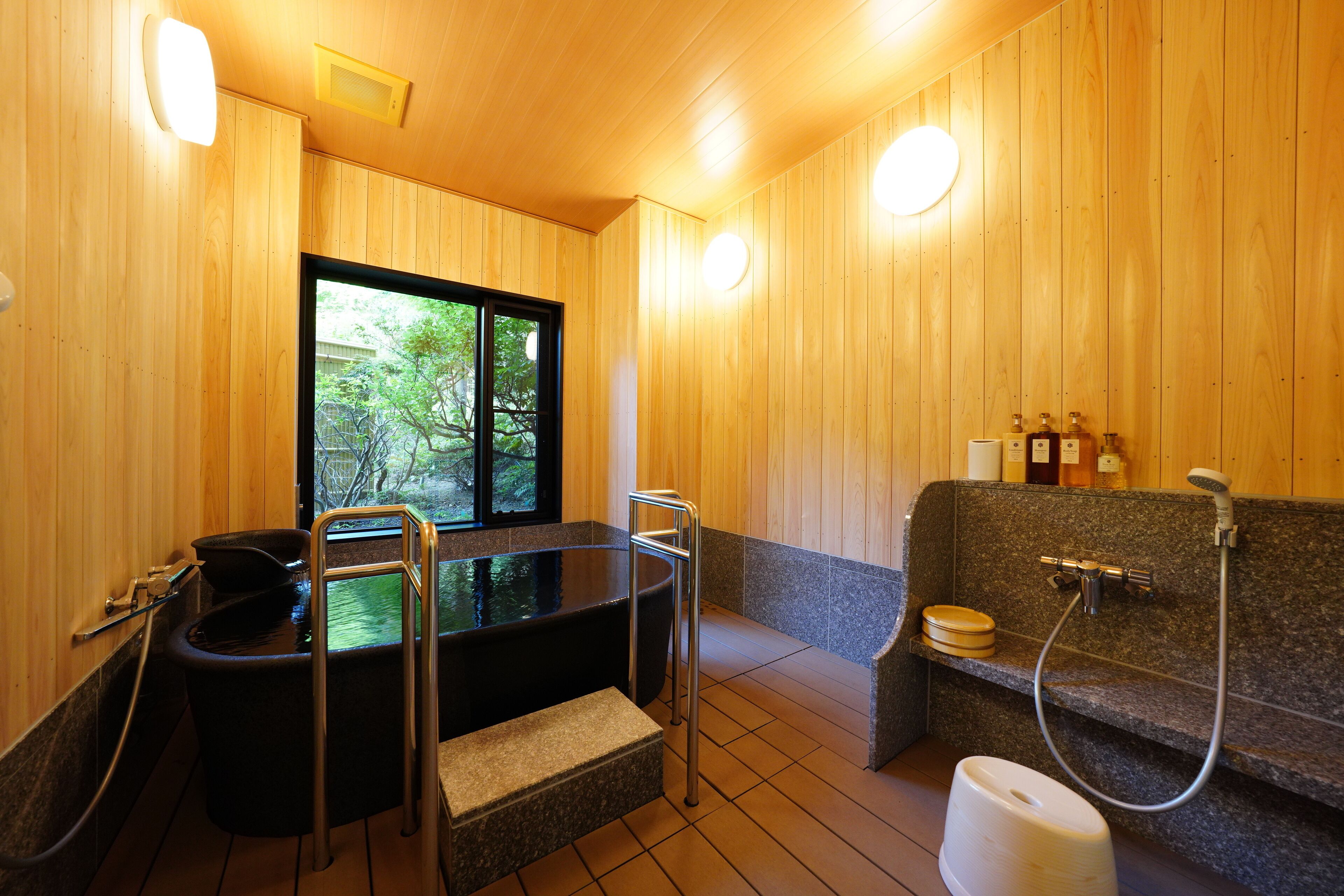 A wooden interior with a sauna, a bathtub, and a shower area.