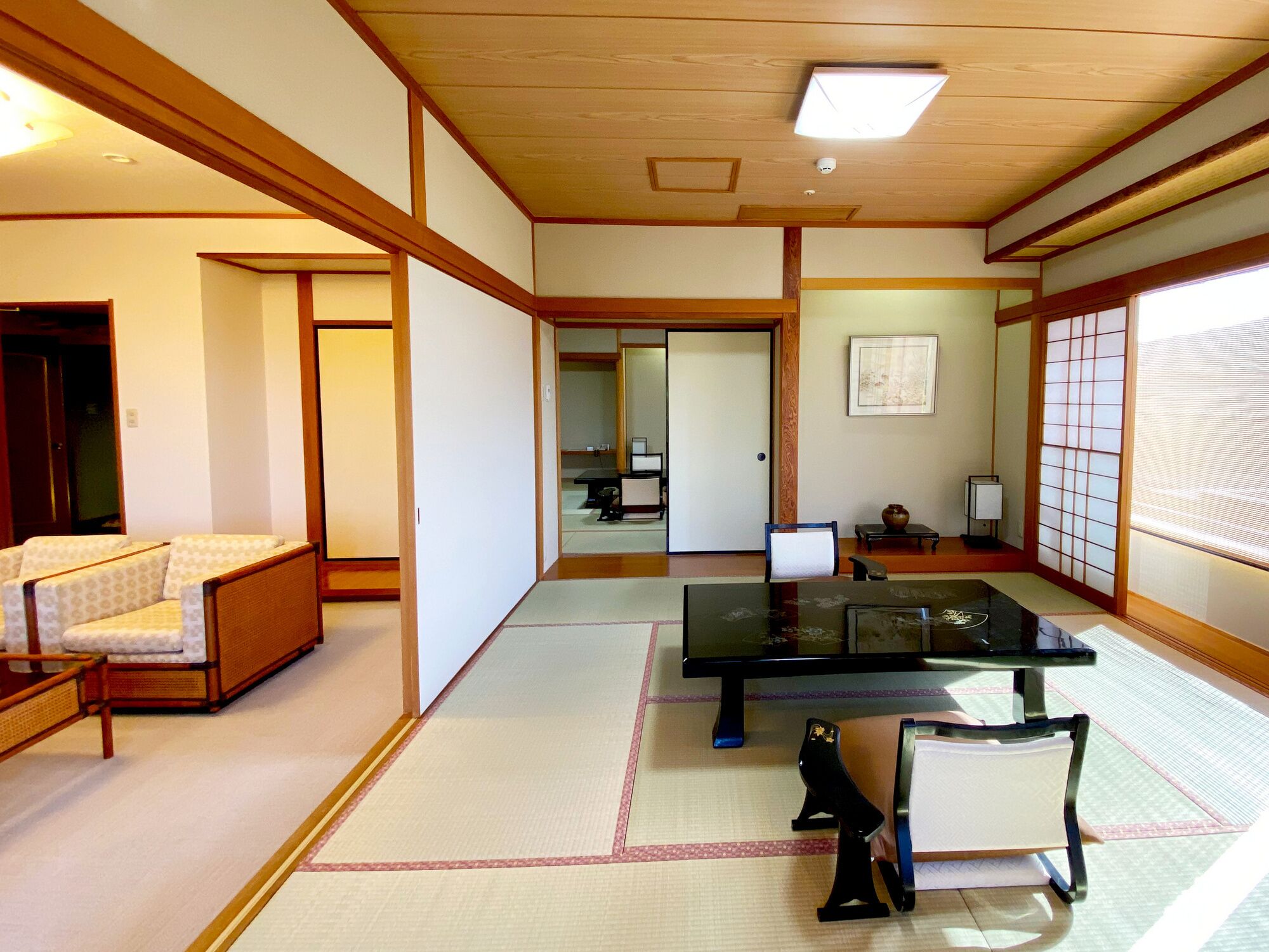 Una habitación japonesa tradicional con suelo de tatami, una mesa baja, una silla y una puerta corredera.