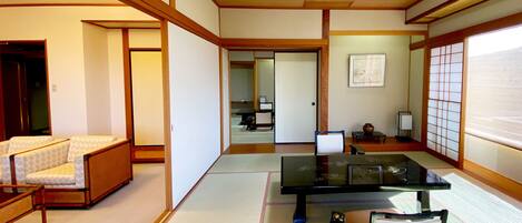Una habitación japonesa tradicional con suelo de tatami, una mesa baja, una silla y una puerta corredera.