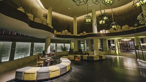 A spacious lobby with tiered seating, large windows, and geometric hanging lights. - Bali Paragon Resort Hotel (Jimbaran)