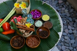 Diversas especiarias e ingredientes dispostos sobre uma folha de bananeira.