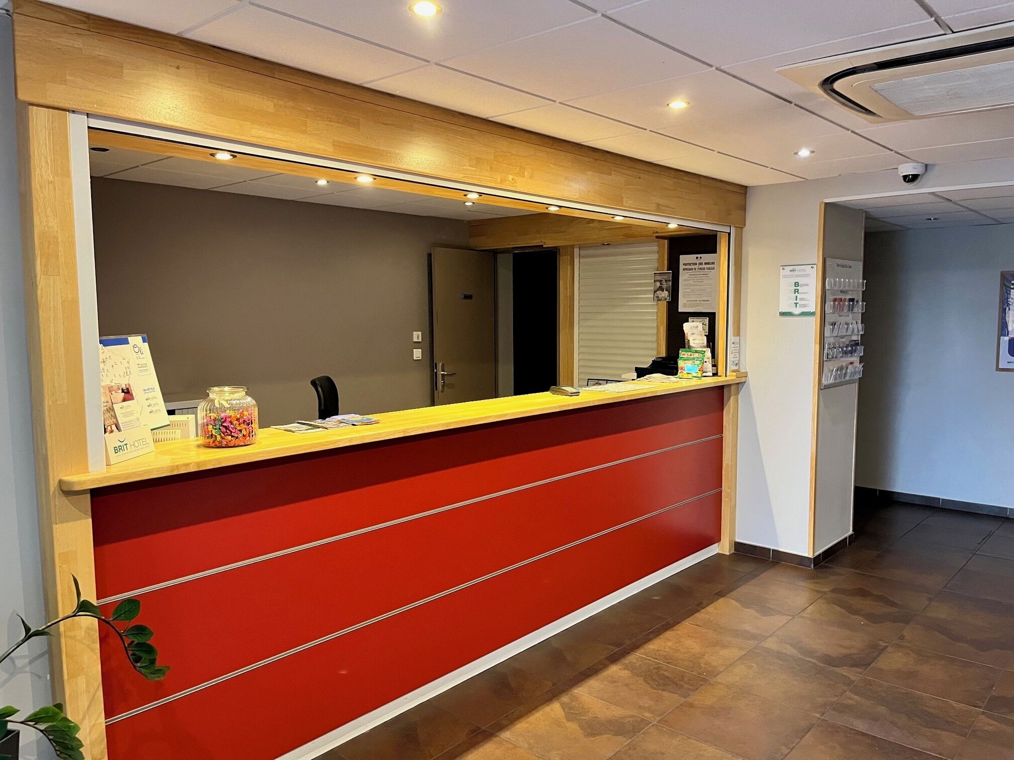 Una recepción con decoración en rojo y amarillo, un espejo encima y una cámara de seguridad en el techo.