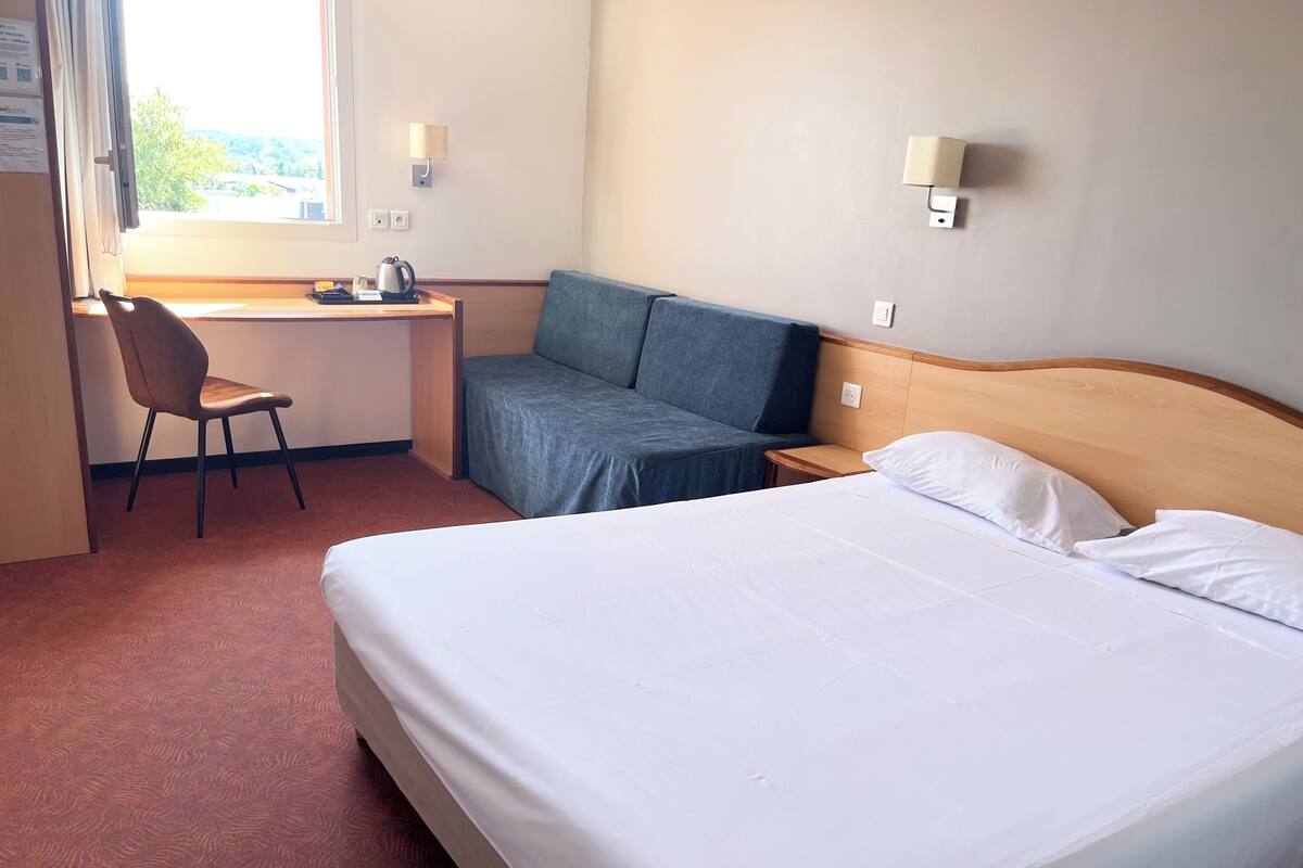 Een hotelkamer met een bed, een bureau, een stoel en een bank.