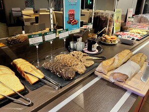Un buffet de petit-déjeuner proposant une variété de pains, de viennoiseries et de tartinades.