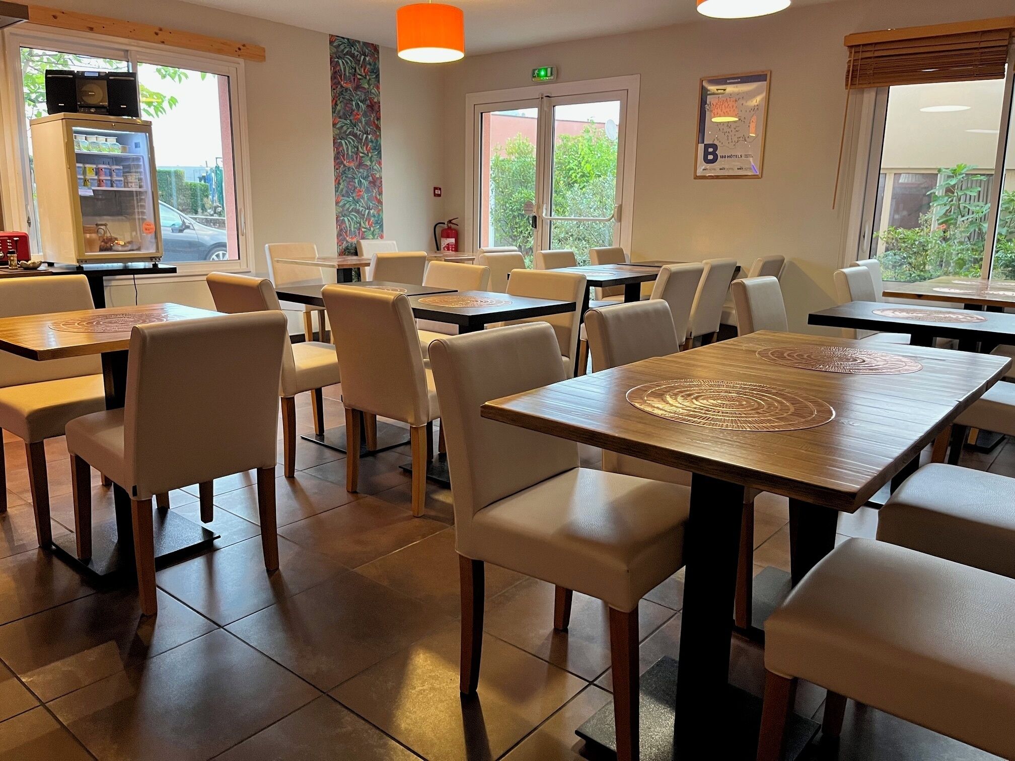 Un restaurant avec plusieurs tables et chaises, une radio posée sur une étagère et un extincteur accroché au mur.