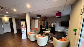 Un hall d’hôtel comprenant des espaces d’attente, un comptoir d’accueil, un réfrigérateur et un téléviseur.