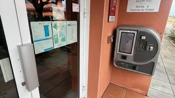A hotel reception area with a reception desk, a digital keycard reader, and informational posters on the wall.