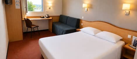 A hotel room with a bed, a desk, a chair, a sofa, and two wall-mounted lamps.