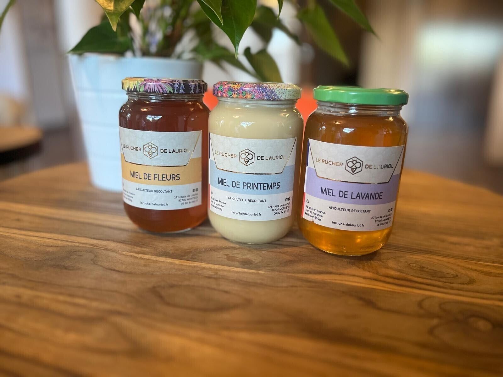 Three jars of honey on a wooden table.