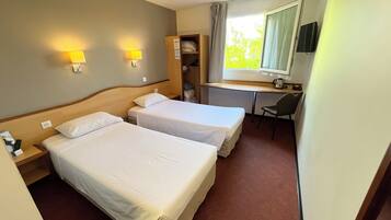 A hotel room with two beds, a desk, a chair, a TV, and a window with curtains.