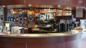 Un espace bar avec des étagères remplies de bouteilles, de verres et un appareil à café.