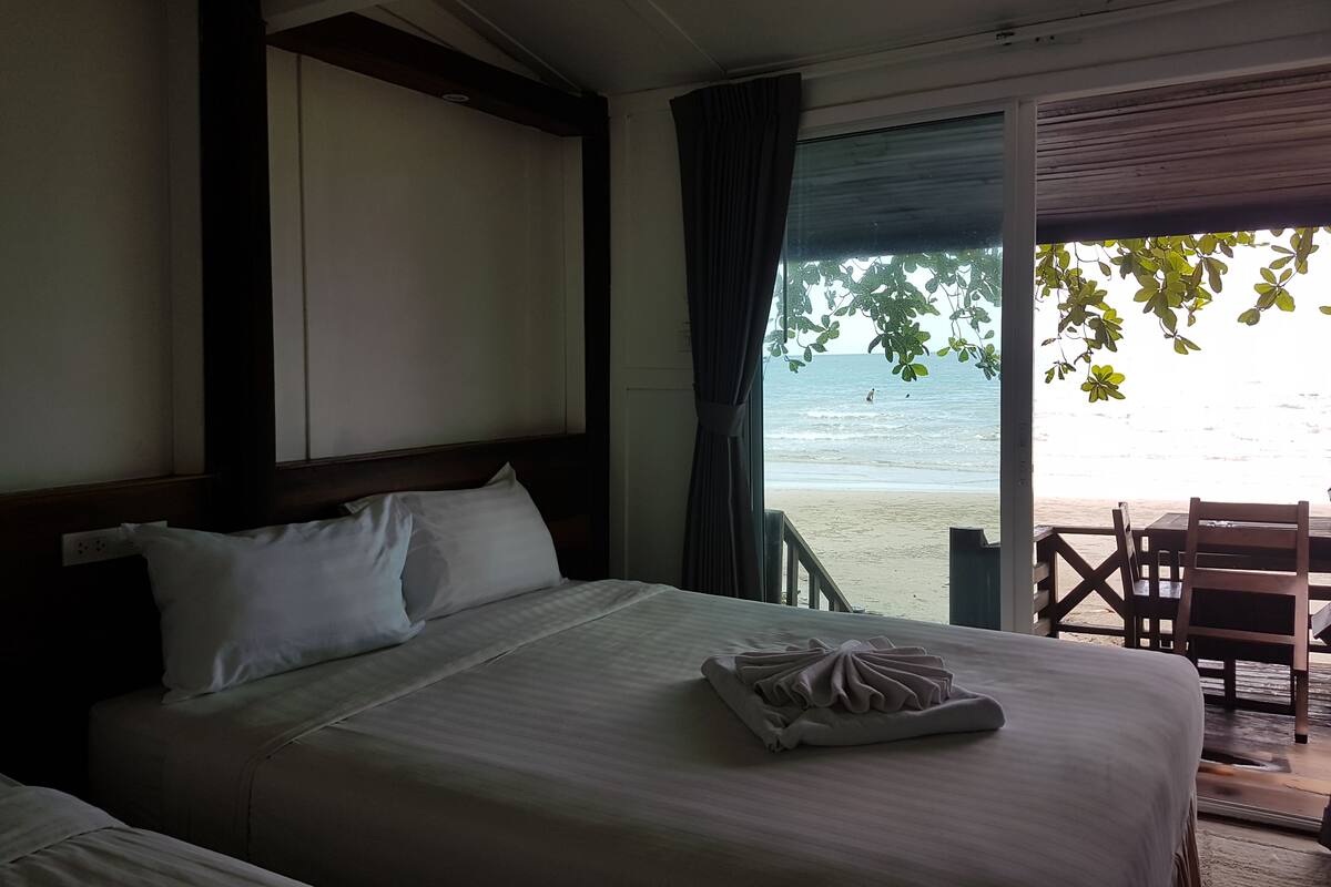 Ein Hotelzimmer mit Bett, Meerblick und einem Tisch mit Stühlen außen.