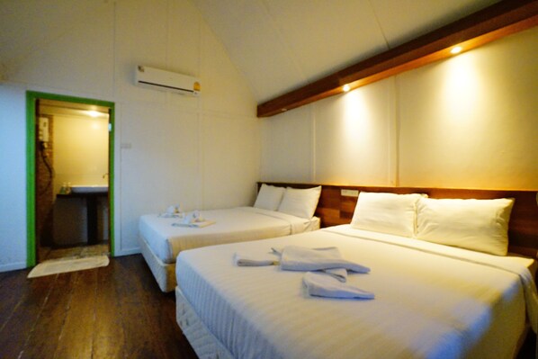 A hotel room with two beds, a wooden headboard, and a small bathroom with a mirror. - Apple Beachfront Resort (Ko Chang)