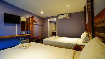 A hotel room with two beds, a TV, an air conditioning unit, and a bathroom visible through an open door.