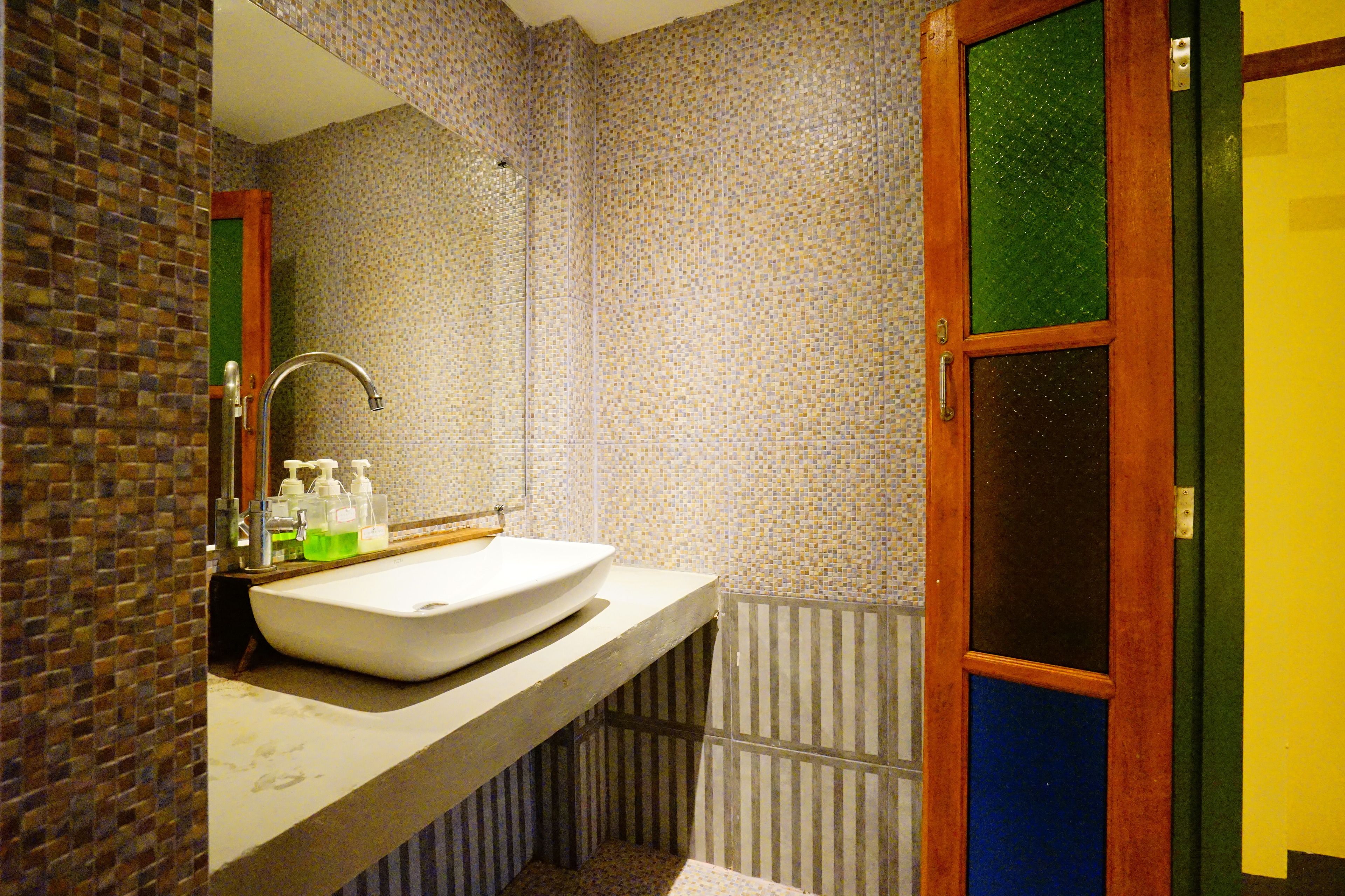 Un bagno con un lavandino bianco, uno specchio e una doccia.