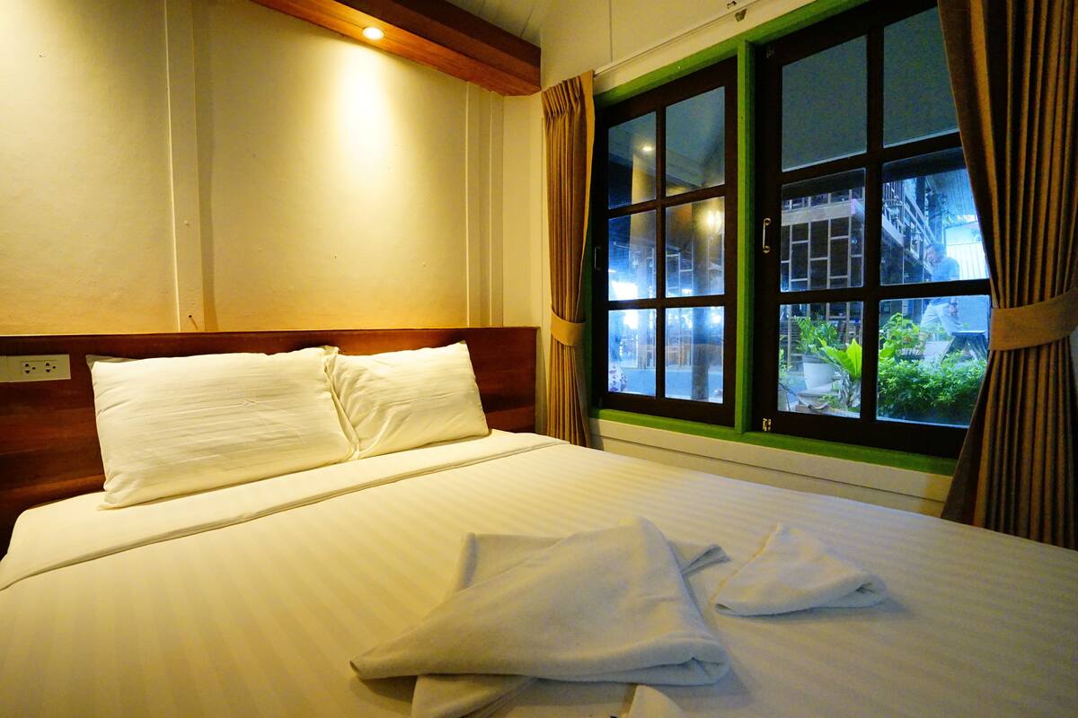 Ein Hotelzimmer mit einem großen Bett, einem Holz-Kopfteil und einem Fenster mit Vorhängen.