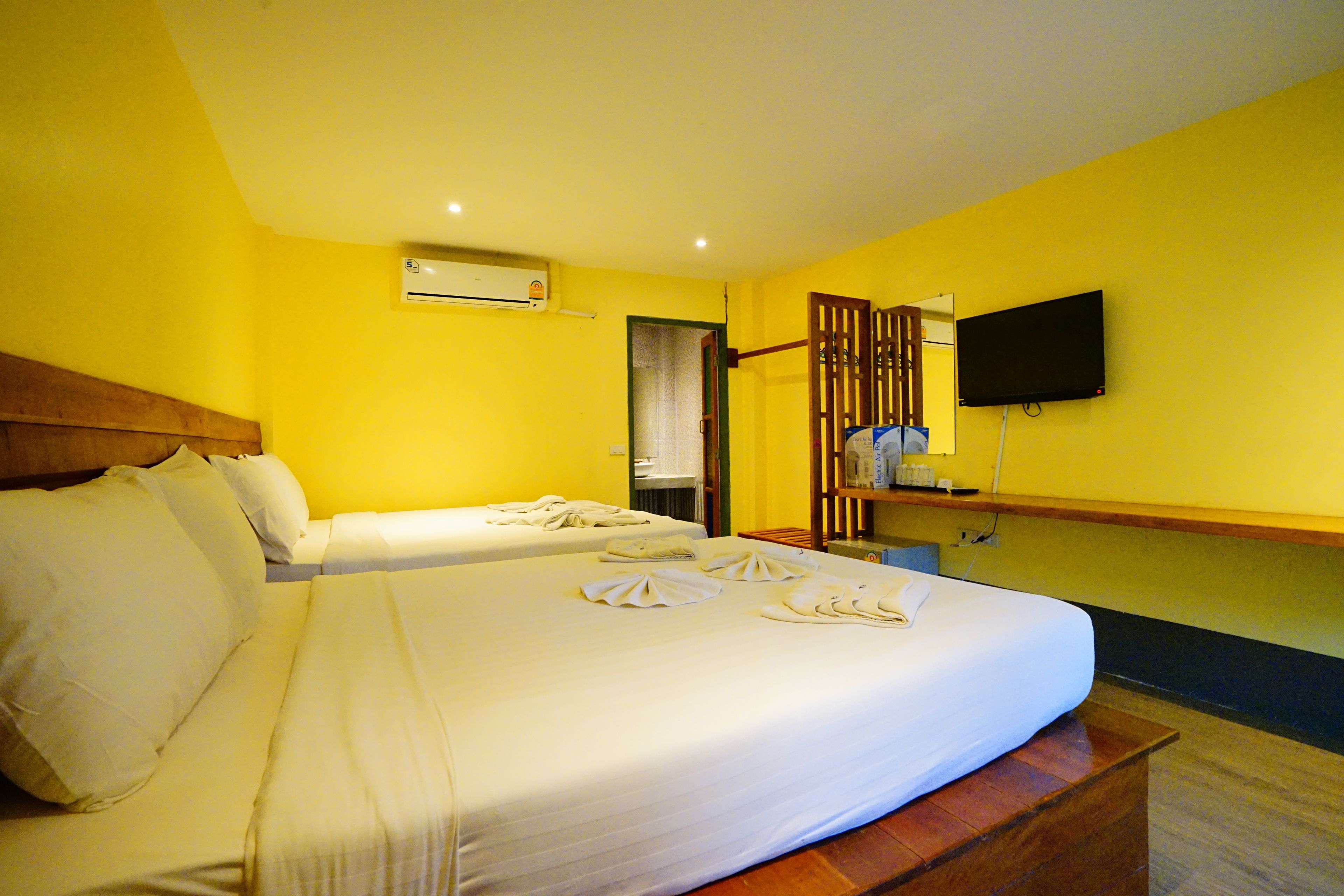 Een hotelkamer met twee bedden, een flatscreen-televisie aan de muur en een airconditioningsunit.