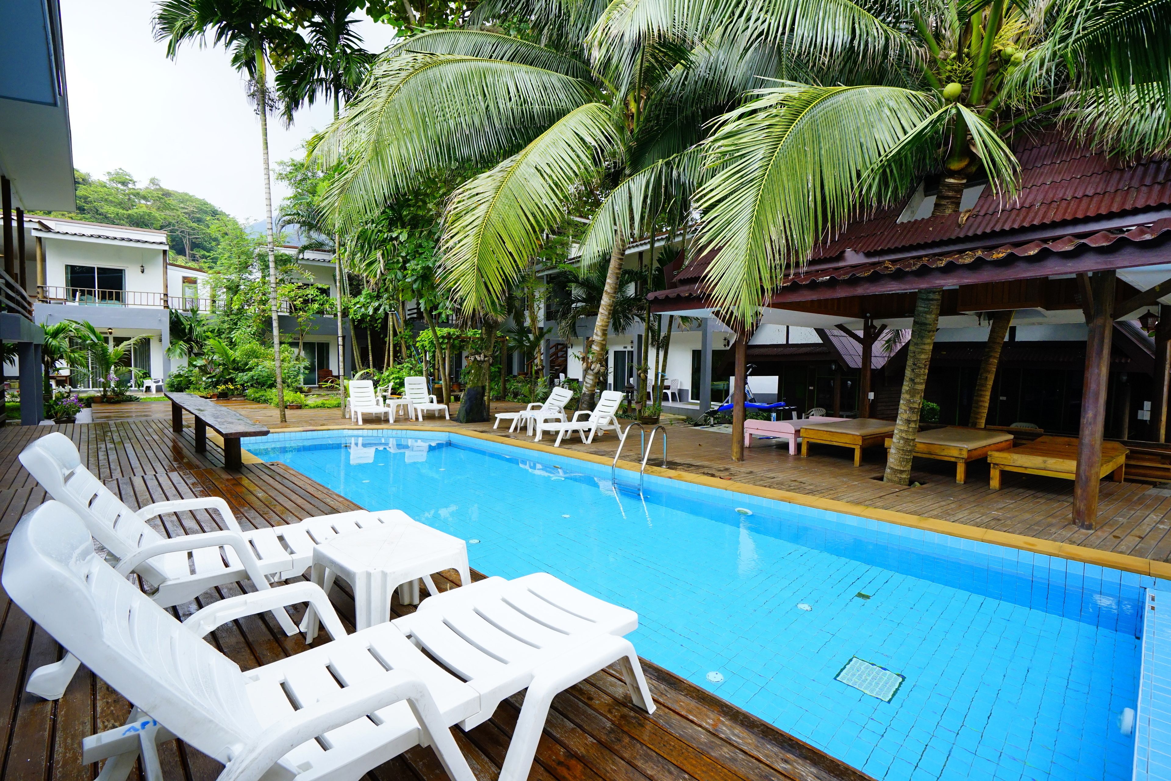 Una piscina al aire libre, sillones reclinables de piscina