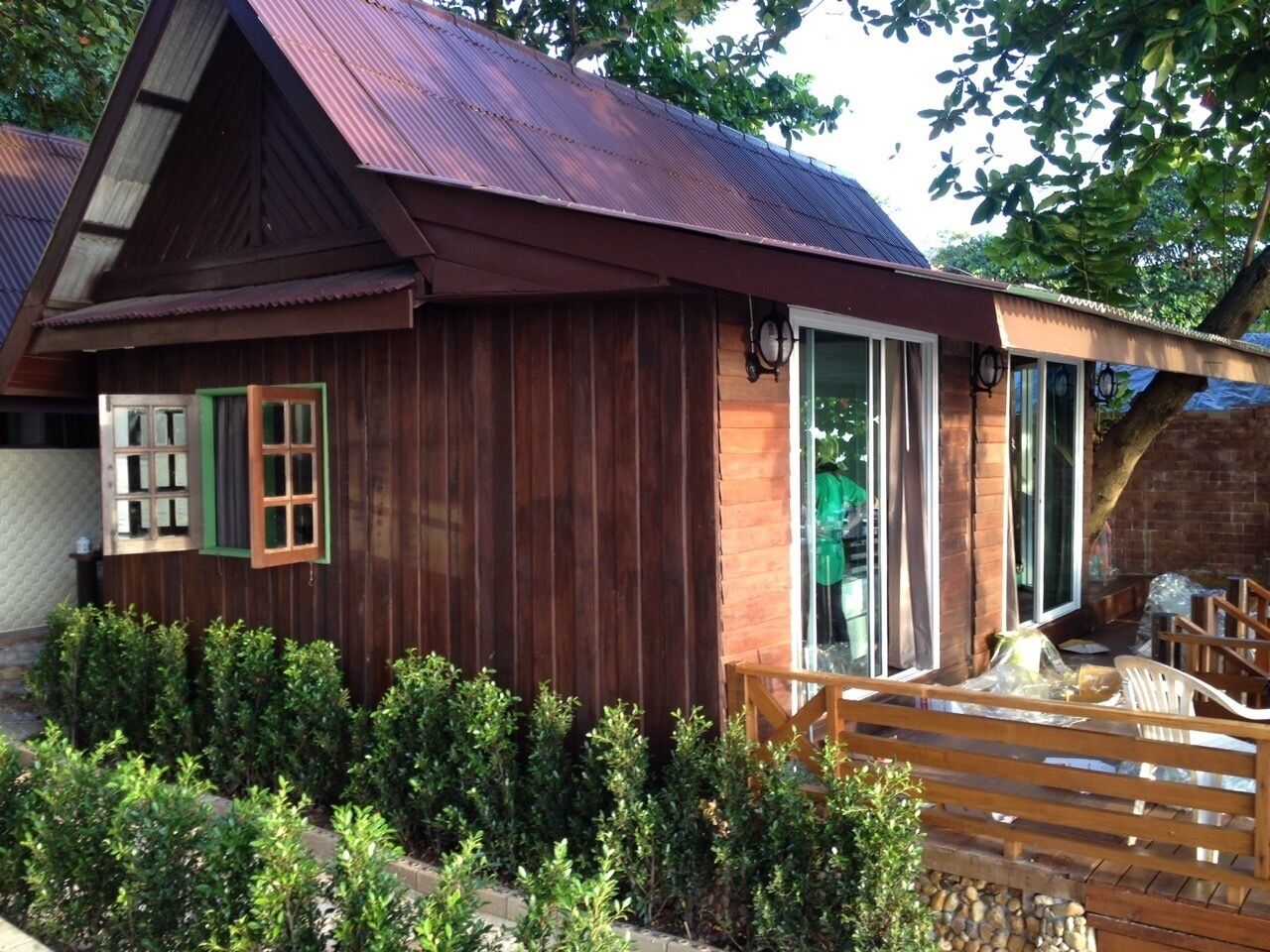 A wooden cabin with a sloped roof, a sliding glass door, and a small porch with a wooden bench.